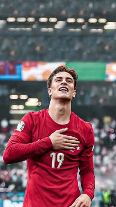 a young man in a red jersey is smiling and holding his arms around his chest