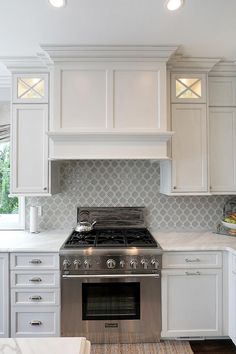 a stove top oven sitting inside of a kitchen next to white cupboards and drawers