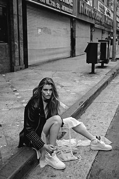 a woman sitting on the curb with her shoes off