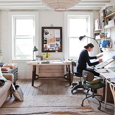 a woman sitting at a desk in front of a window with lots of books on it