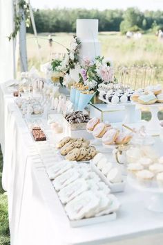 a table filled with lots of desserts on top of a white table cloth covered table