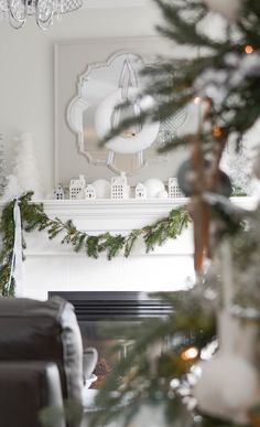 a living room decorated for christmas with white and silver decorations on the fireplace mantel