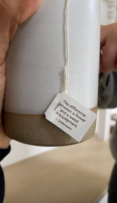 a person holding a white vase with a tag on it that says, send message