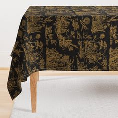 a black and gold table cloth with golden designs on it, in front of a white rug