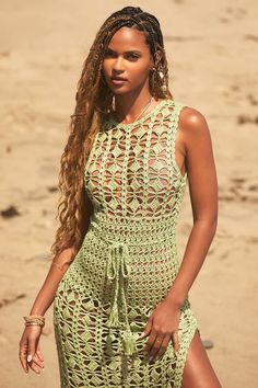 a woman in a green crochet dress on the beach