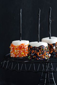 halloween cupcakes with sprinkles and black icing on a cake stand