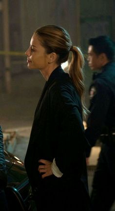 a woman standing in front of a police car with her back turned to the camera