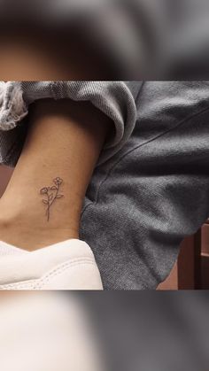 a woman's foot with a small flower tattoo on her left side ribcage