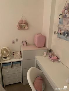 a baby's room with white furniture and pink accessories on the desk, along with other items