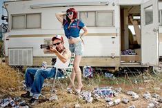 two people sitting on chairs in front of a camper with beer cans all over the ground