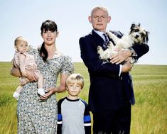 an older man, woman and two young children standing in a field holding small dogs