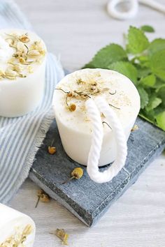 two soaps sitting on top of a blue towel next to green leaves and flowers