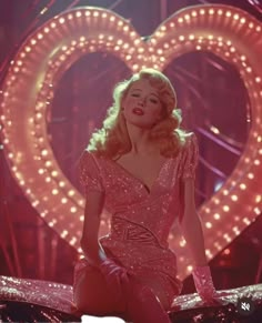 a woman sitting on top of a bed in front of a heart shaped light display