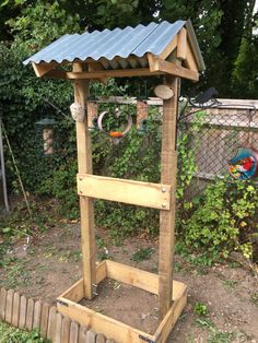 a small wooden structure in the middle of a yard with a bird feeder on it's side