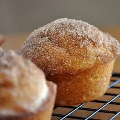 two muffins sitting on top of a cooling rack with powdered sugar over them