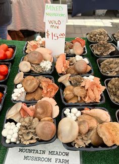 several trays of mushrooms and tomatoes on display at a farmer's market for sale