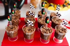 desserts are arranged in small cups on a red tray with black and white checkered flags