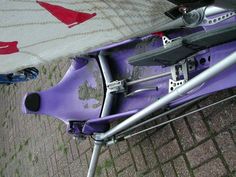 a purple kayak sitting on the ground next to a white and red towel,