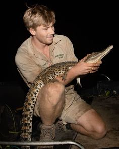 a man holding an alligator in his hands