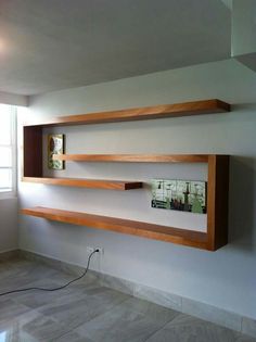 two wooden shelves are on the wall in this empty room