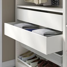 an open drawer in a closet with several pairs of shoes on the bottom shelf and one pair of slippers below it