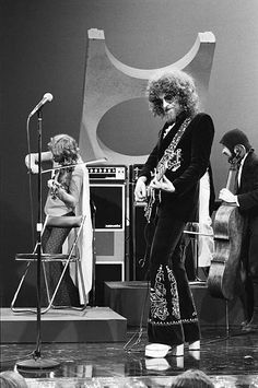 an old photo of some people on stage with guitars and microphones in front of them