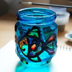 a blue glass jar sitting on top of a table next to a notepad and pen