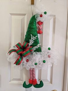 a christmas door hanger decorated with candy canes, stockings and an elf's hat