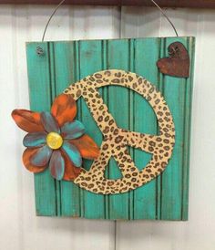 a wooden sign with a flower and peace sign on the front hanging from a hook