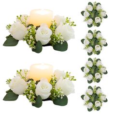 white roses and greenery are arranged next to a lit candle