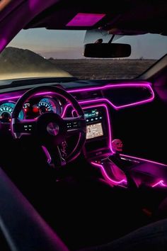 the interior of a car is lit up with purple lights and steering wheel, along with dashboard controls