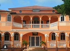 an orange house with white balconies and columns