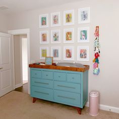 a baby crib in the corner of a room with many pictures on the wall