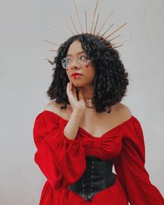 a woman in a red dress is posing with her hands on her chin and looking at the camera