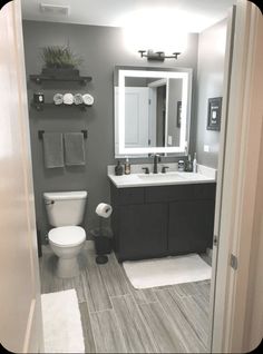 a white toilet sitting next to a sink in a bathroom under a mirror and lights