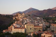 a small village nestled on the side of a hill with mountains in the back ground