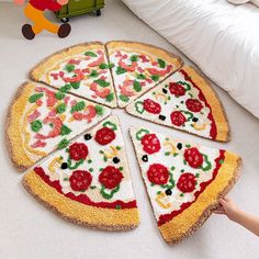 a child's hand reaching for a slice of pizza on the floor next to a bed