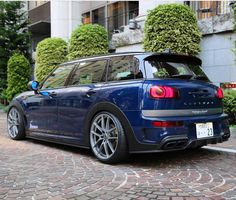 a blue minivan parked in front of a building on a cobblestone street