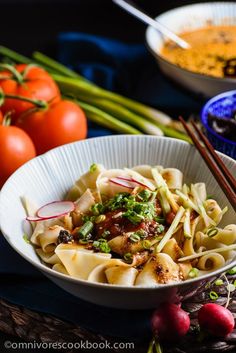 a bowl filled with noodles and vegetables next to chopsticks