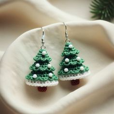 small christmas tree earrings with white pearls and green crochet on the bottom, sitting on a napkin