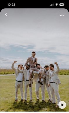 a group of men standing on top of each other in front of a lush green field