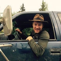 a man sitting in the driver's seat of a truck with his hat on