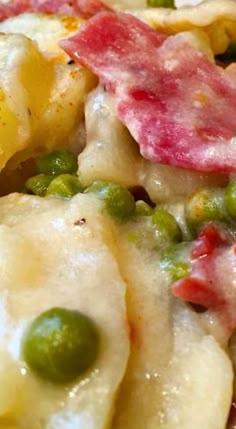 a close up view of some pasta with peas and ham on it, as well as cheese