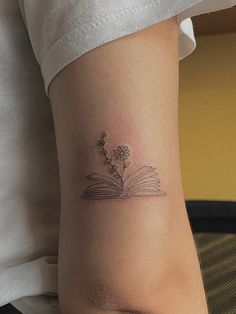 a woman with a book tattoo on her leg, reading and holding an open book