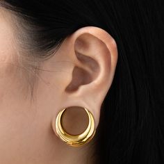 a close up of a person wearing gold earring on their left and right ear