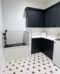 an empty kitchen with black cabinets and white counter tops, including a sink and dishwasher