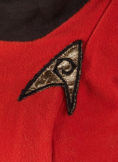 the star trek insignia is on top of a red jacket with black and silver trim