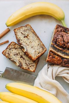 sliced banana bread with cinnamon swirl on top and two bananas next to it, along with other ingredients