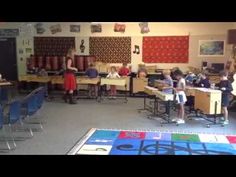 a classroom filled with lots of desks and children sitting at their desks in front of them