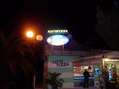 a man standing in front of a fast food restaurant at night with the lights on